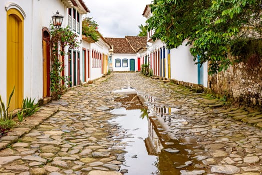 Cobblestone street with colorful colonial houses and reflections in the puddles in the historic city of Paraty, Rio de Janeiro, Brazil