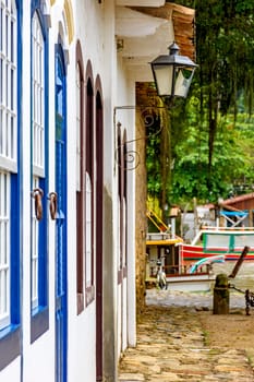 Colonial style house facades with old metal lantern and boats in the background in the historic town of Paraty, Rio de Janeiro, Brazil