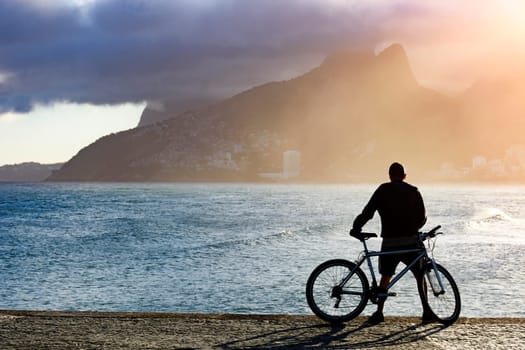 Cyclist in front of the sea during late afternoon at Arpoador beach in Ipanema, Rio de Janeiro