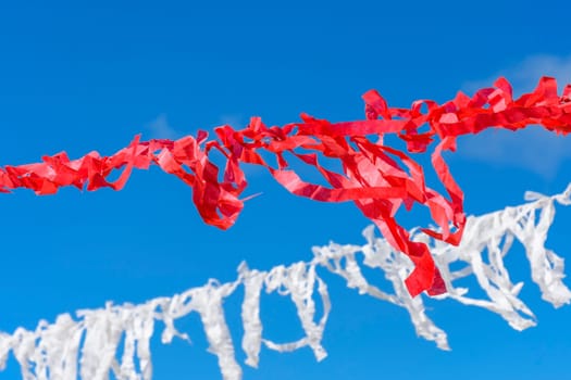 Decorative vivid red and white ribbons prepared for a religious festival in the city of Lavras Novas in Minas Gerais swaying in the wind with blue sky in background