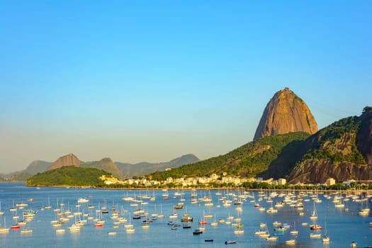 Guanabara Bay with boats floating on the water and the Sugarloaf Mountain in the background during the summer afternoon