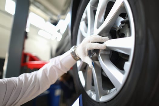 Mechanic changes car wheel in auto repair shop. Tire service concept