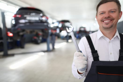 Auto mechanic is holding a wrench at service station. Garage work and auto repair concept
