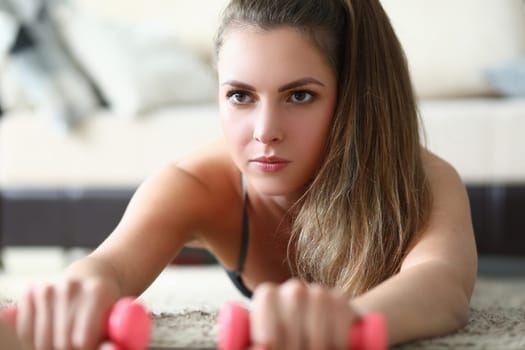 Portrait of beautiful woman with dumbbells on floor. Home fitness and sport goal concept