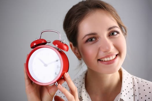 Portrait of beautiful smiling young woman holding alarm clock for ten o'clock. Day planning and time management concept