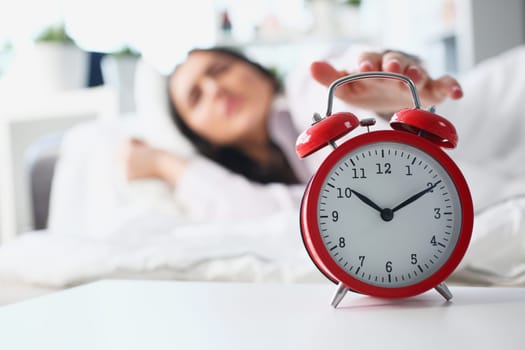 Dissatisfied woman turns off the alarm clock in bed. Insomnia stress and late waking up