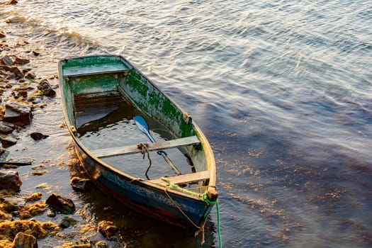 Old wooden fishing boat floating over seawater at sunset