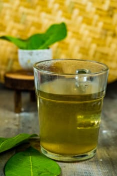 Fresh tea made of bay leaf in a glass on the table with bamboo tray background.