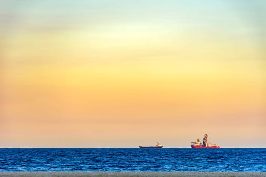 Ships on the horizon during tropical sunset at Copacabana beach in Rio de Janeiro