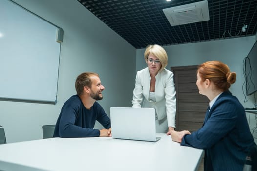 Blond, red-haired woman and bearded man in suits in the office. Business people are negotiating in the conference room