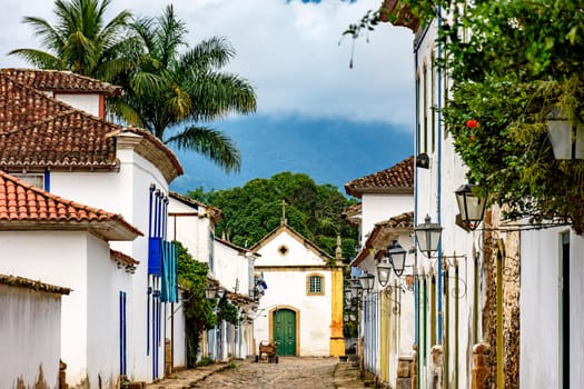 Old street with its lanterns, colonial style houses, cobblestone pavement and historic church in the background in Paraty, south coast of Rio de Janeiro