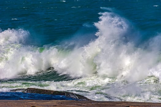 Strong waves crashing against rocks during storm on a sunny day