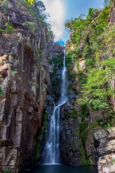 Stunning waterfall called Veu da Noiva between moss covered rocks and the vegetation of an area with nature preserved in the state of Minas Gerais, Brazil