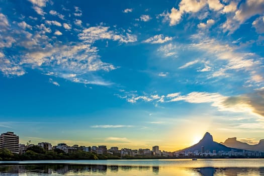 Sunset at Rodrigo de Freitas lagoon with the buildings and hills of the city of Rio de Janeiro reflected in the water