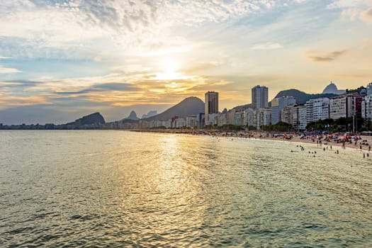 Sunset on the famous Copacabana beach with the sea, sand, mountains and buildings in the city of Rio de Janeiro