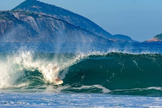 Surfer inside the tube in a wave at Ipanema beach, Rio de Janeiro with islands in the background