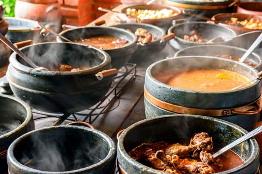 Typical Brazilian foods placed in clay pots and on a metal plate of a traditional wood stove