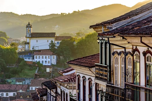 View of historic colonial style houses and church in the background on the hills of Ouro Preto city, Minas Gerais state, Brazil