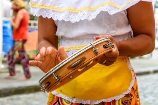 Woman in colorful ethnic clothes playing tambourine during a samba performance in Salvador, Bahia