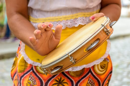 Young woman in colorful clothes playing the tambourine during a samba performance in Salvador, Bahia.