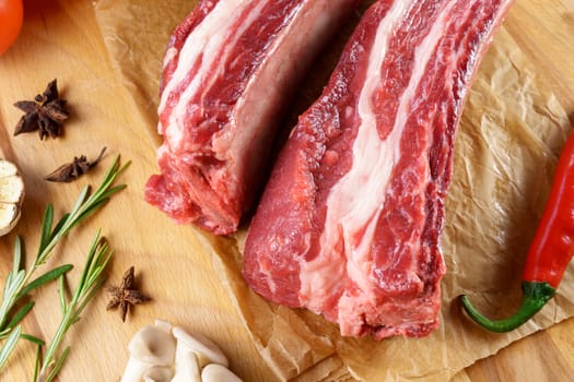 Raw Tomahawk steak on wooden background with spices. Cooking meat