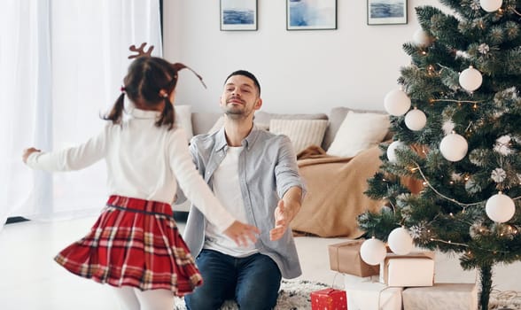 Little girl runs to her father. Celebrates New year together at home.