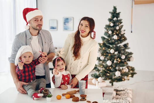 Sits against fir. Beautiful family celebrates New year and christmas indoors at home.