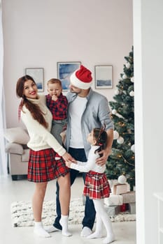 Standing together. Beautiful family celebrates New year and christmas indoors at home.