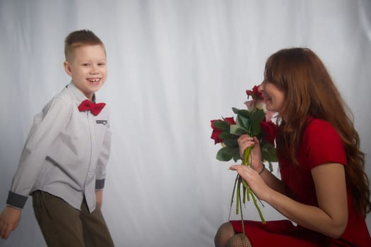 Woman with boy with flower. Mom with son on a white background in mothers Day. Family portrait with mother and boy having fun together