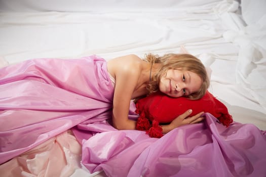 Portrait of cute kid girl posing in pink beautiful dress on white background. Model in studio looking as gentle magic princess from fairy taly having photo shoot on white background