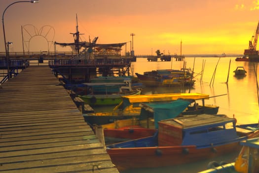 View of wooden pier on boat dock wharf in Gresik, East Java, Indonesia during sunrise