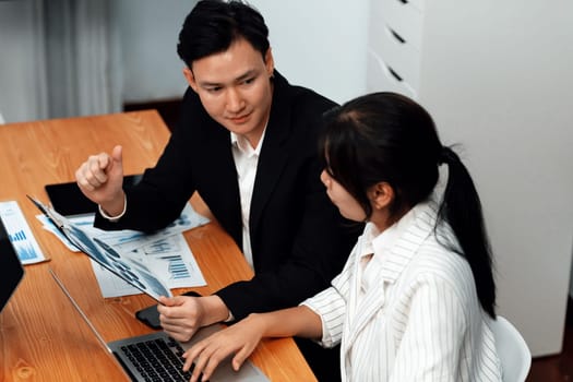 Harmony in office concept as business people analyzing dashboard paper together in workplace. Young colleagues give ideas at manager desk for discussion or strategy planning about project.