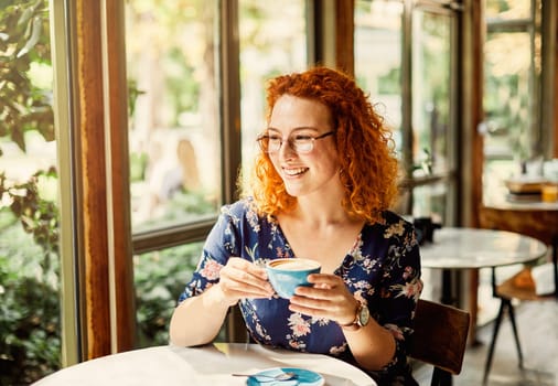 Portrait of a beautiful young woman drinking cappuccino in a cafe