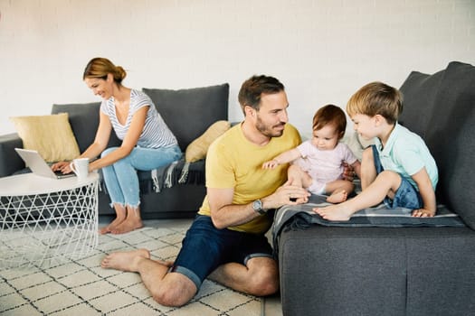 Happy family at home, mother working on laptop from home