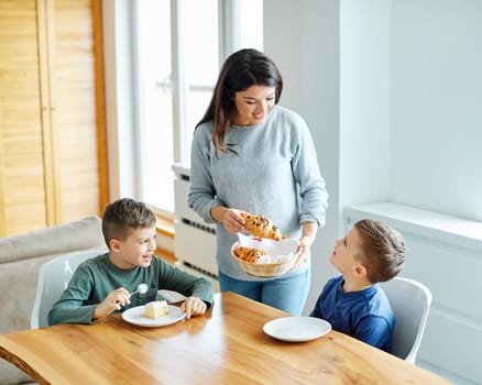 mother and sons eating breakfast and having fun at home