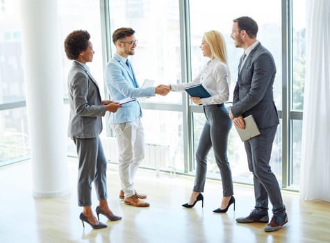 portrait of a young beautiful businesspeople shaking hands introducing each other in a new office