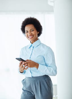portrait of a young black business woman holding a smartphone in the office