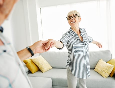 Happy active healthy senior couple dancing in living room at home