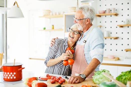 Portrait of happy senior couple prepering meal in kitchen
