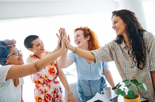 A group of young business women celebrating with high five in the office or in classroom
