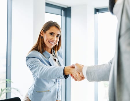 portrait of a young beautiful businesswoman shaking hands introducing each other in the office