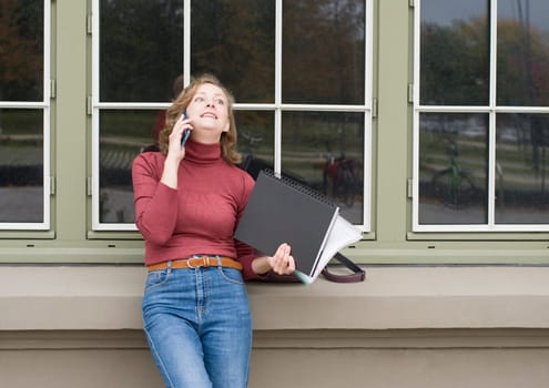 a young caucasian girl returns to college, stands with a backpack and notebooks and talks on the phone in a laugh, back to school, High quality photo