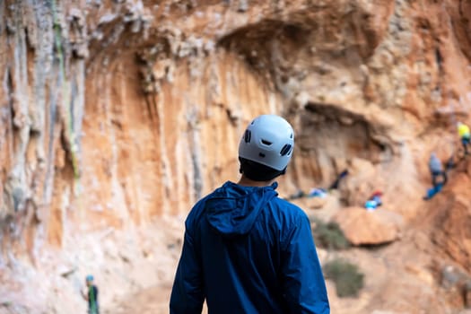 Hiker stands against the background of beautiful red rocks, a rock climber in a helmet prepares for outdoor training, man leads an active life style.