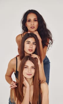 Three young women in lingerie together indoors. White background.