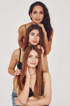 Three young women in lingerie together indoors. White background.