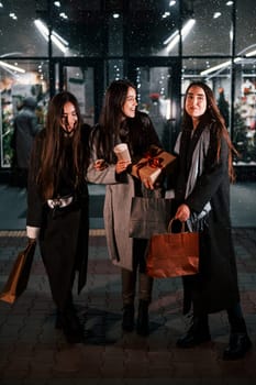 After shopping. Three cheerful women spends Christmas holidays together outdoors. Conception of new year.