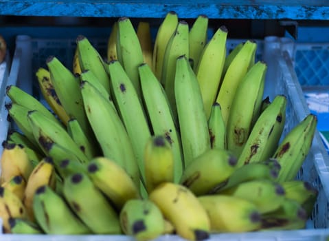 Bunch of many green and some yellow bananas in a street market. High quality photo