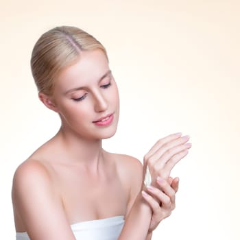 Personable woman applying moisturizer cream on her hand for perfect skincare treatment concept in isolated background. Beauty care cream applying on body by female model with soft natural makeup.