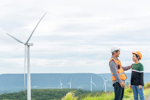 Engineer with his son on a wind farm atop a hill or mountain in the rural. Progressive ideal for the future production of renewable, sustainable energy. Energy generation from wind turbine.