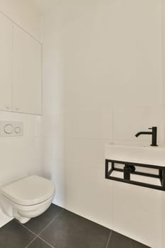 a white bathroom with black tile flooring and wall mounted toilet in the corner, there is a mirror on the wall